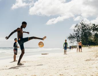 Men playing soccer on the beach